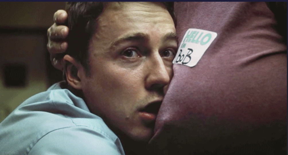 Der Erzähler in Fight Club, an Bobs Schulter gepresst, mit „Hello my name is"-Aufkleber